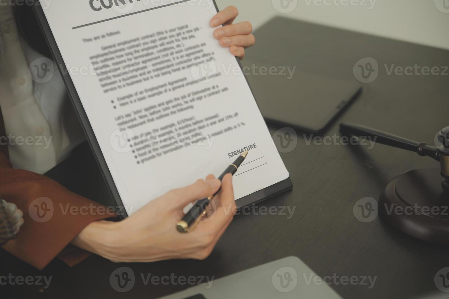Justice and Law concept. Legal counsel presents to the client a signed contract with gavel and legal law or legal having team meeting at law firm in background photo