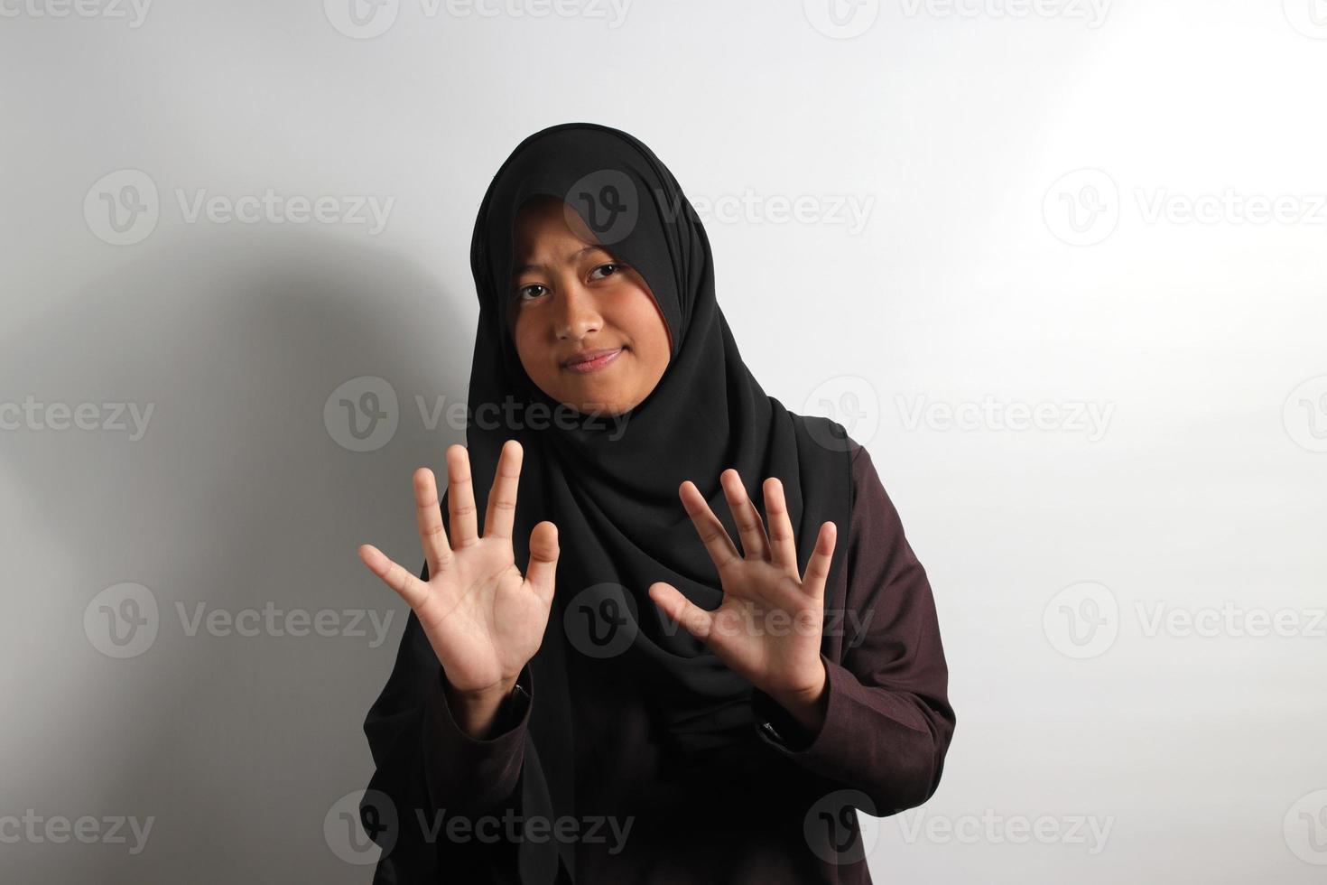 Displeased young Asian girl in hijab making stop gesture isolated on white background. photo