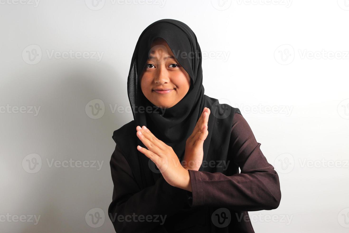 Displeased young Asian girl in hijab making stop gesture isolated on white background. photo