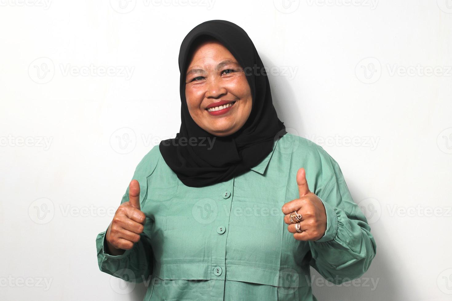 Cheerful Middle aged Asian women wearing hijab making double thumbs up gesture photo