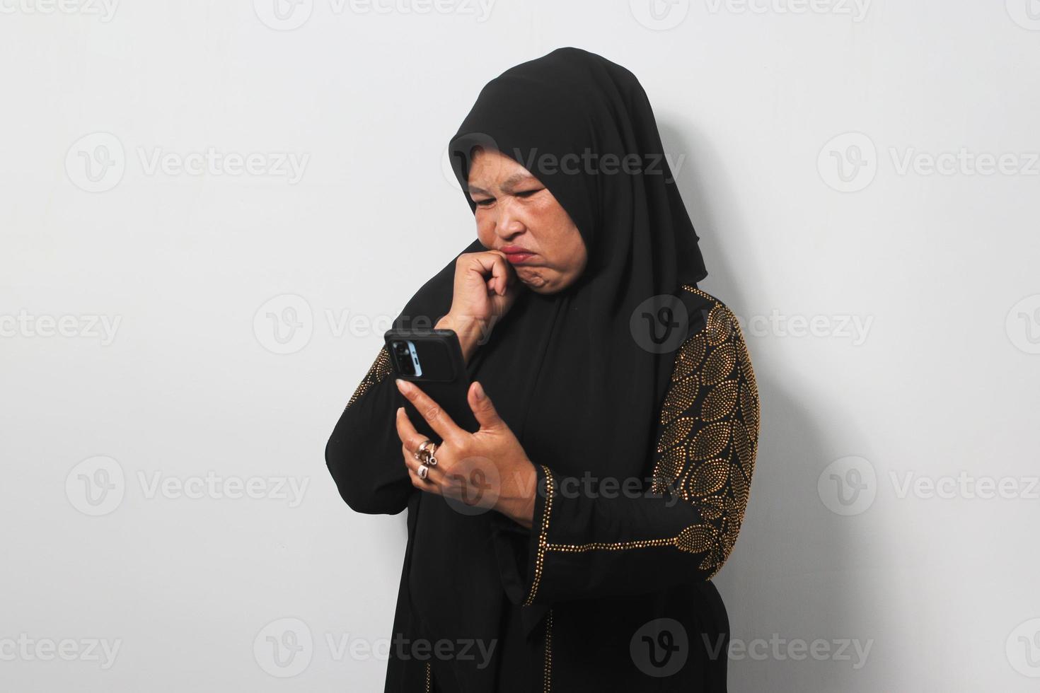 medio Envejecido asiático mujer vistiendo hijab siente triste leyendo malo Noticias en móvil teléfono foto