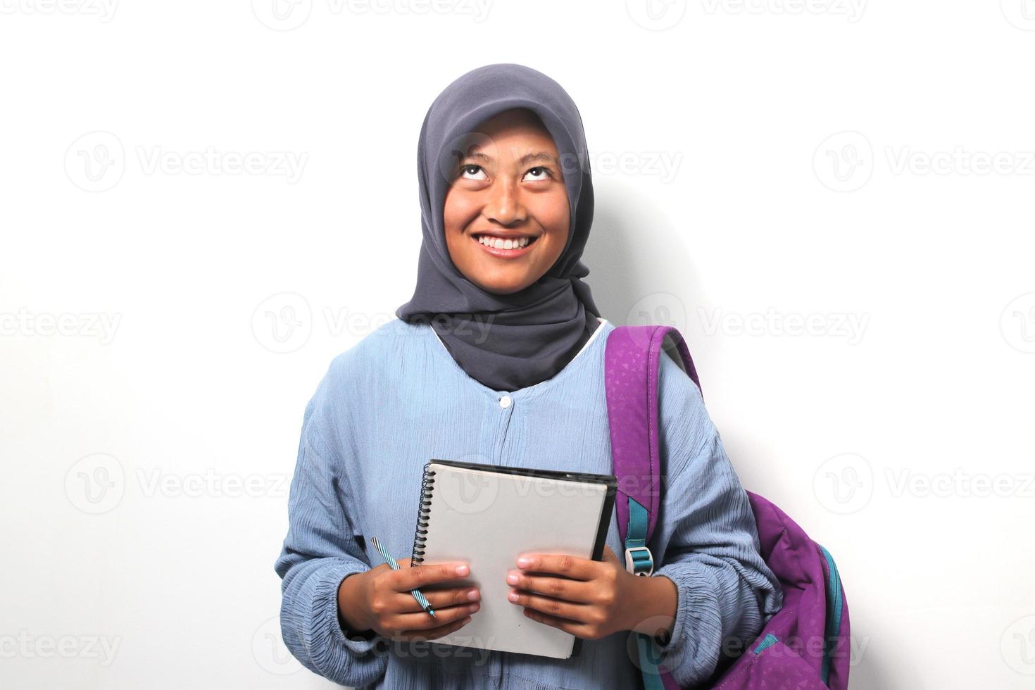 Young Asian girl student wearing hijab and backpack, looking up isolated on white background. photo