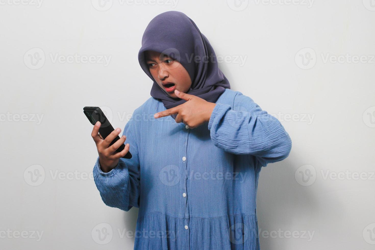 Young Asian girl in hijab is annoyed while using mobile phone photo