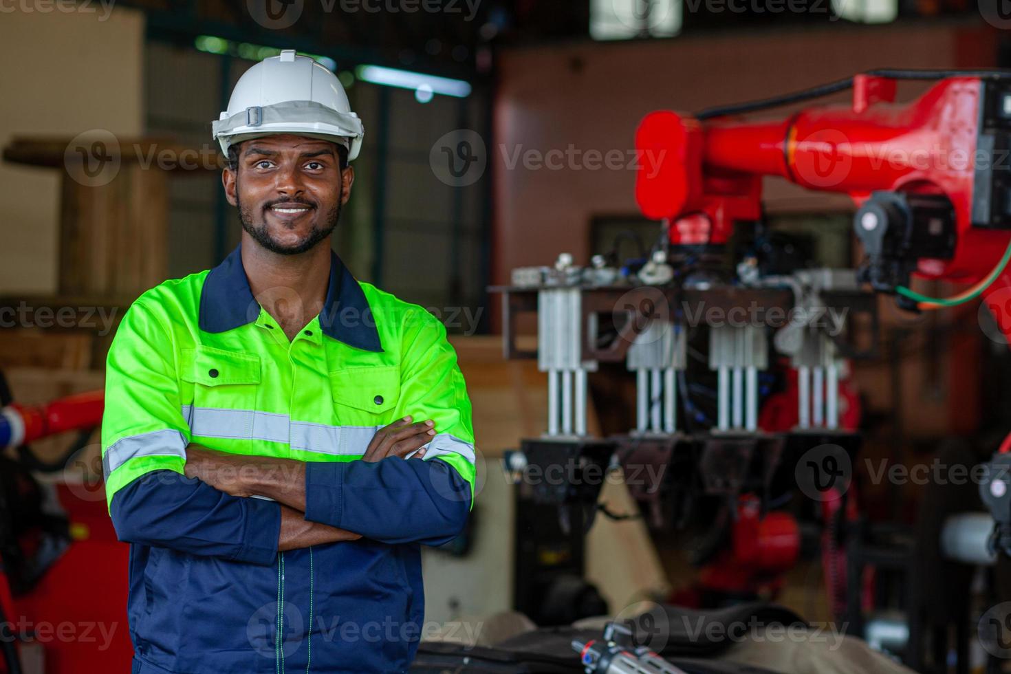 Portrait of an African American factory worker working with a robotic arm in a factory. Industrial robot background for automated production technology. looking at camera photo