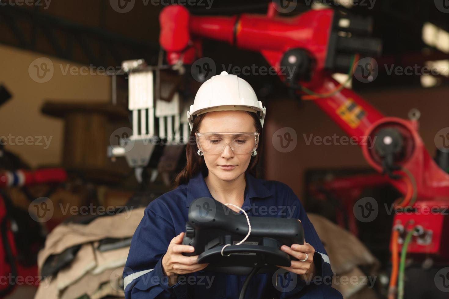 A beautiful engineer controls an automated robotic arm in a smart factory. Welding robots in industrial plants. photo
