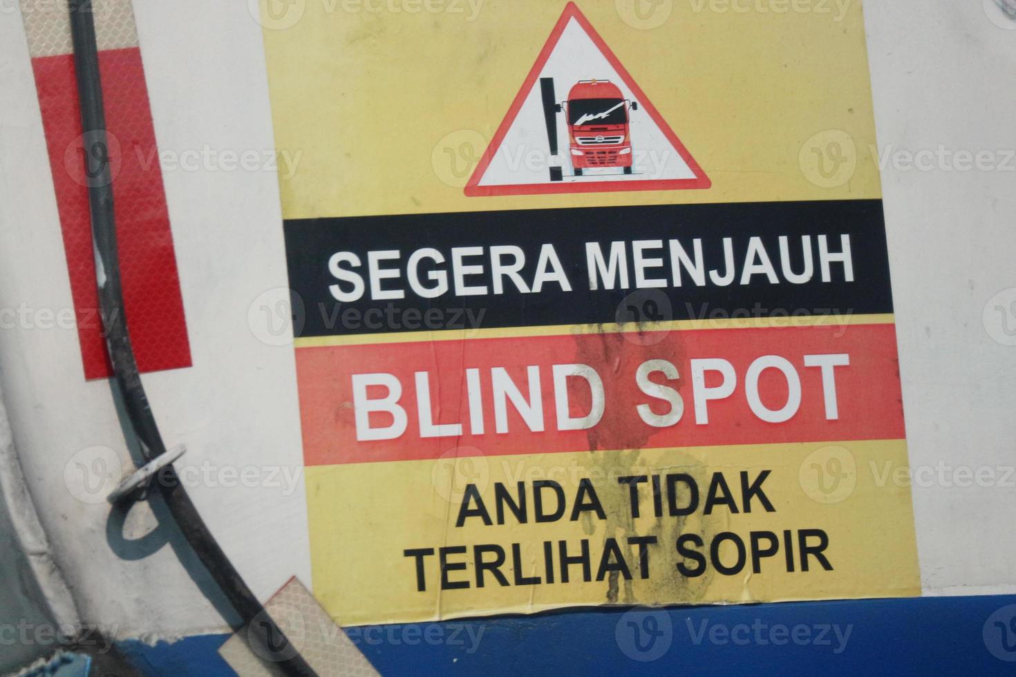 A warning sign for a fuel tank, namely immediately away from BLIND SPOT you are not visible to the driver. photo