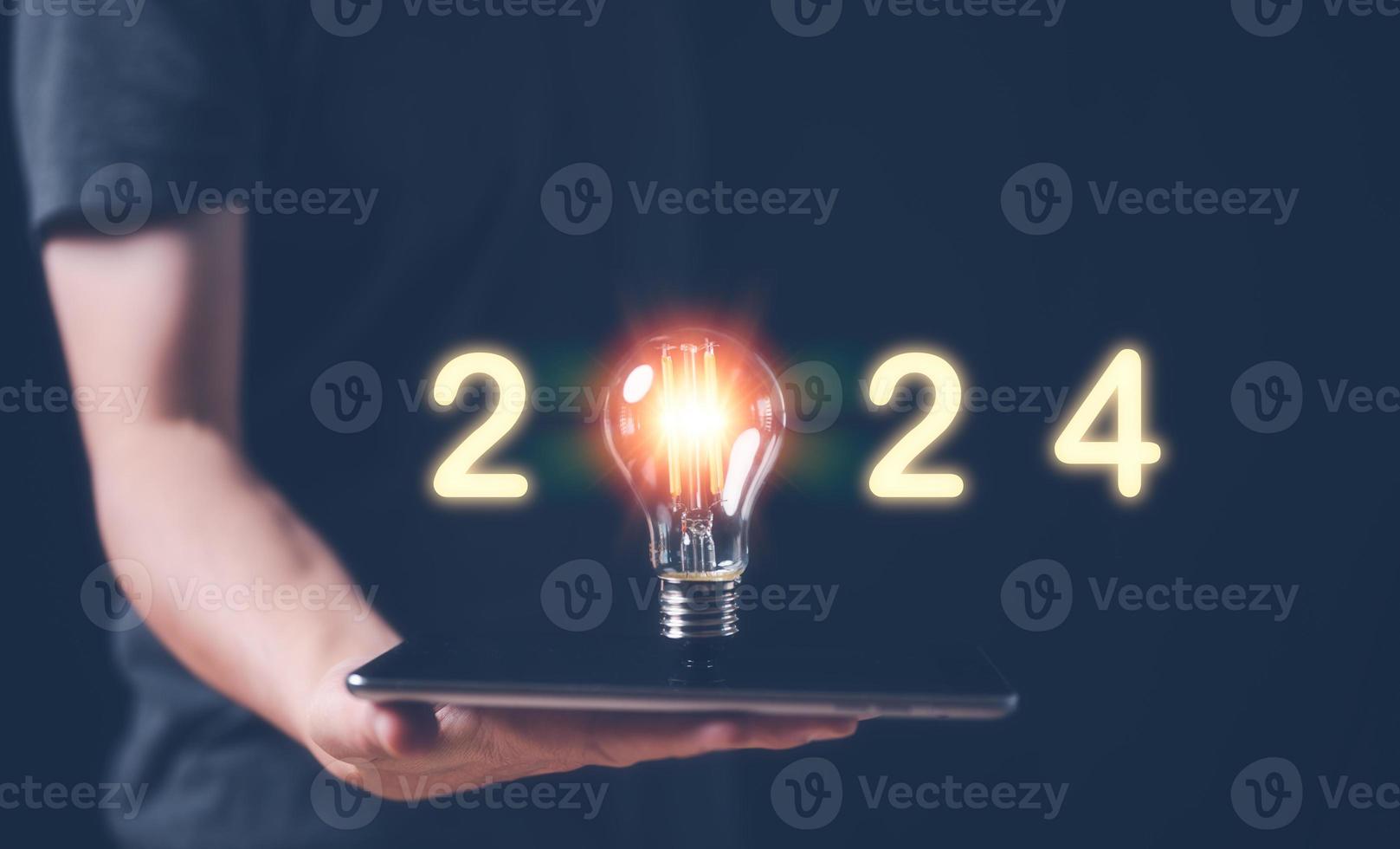 new year business plan and strategy for 2024, man holding glowing lightbulb with 2024 number for creative thinking idea for start new business concept. photo