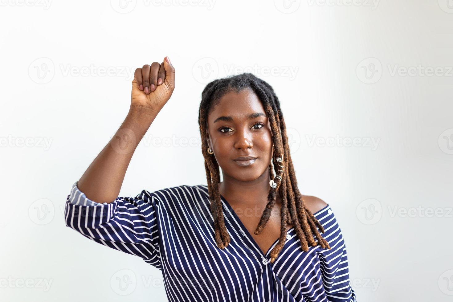 elevado mano de joven africano mujer apretado dentro puños en ligero antecedentes. detener racismo concepto foto