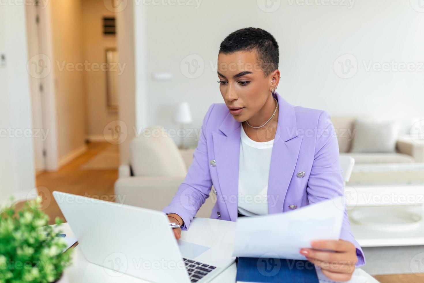 Beautiful African American woman freelancer noting information for planning project doing remote job via laptop computer. woman laughing while reading email on modern laptop device . photo