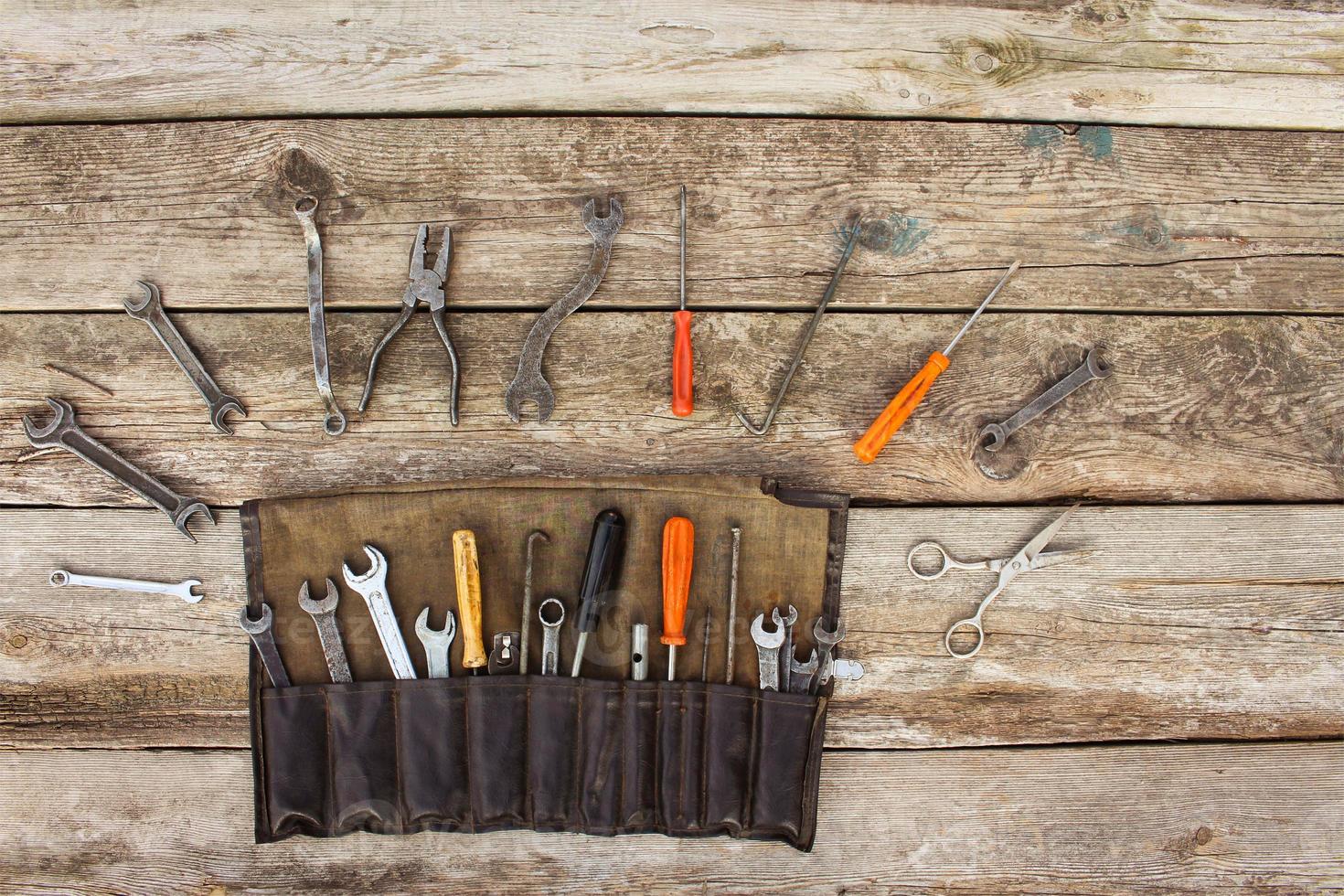 Old tools in bag on wooden background. Top view photo