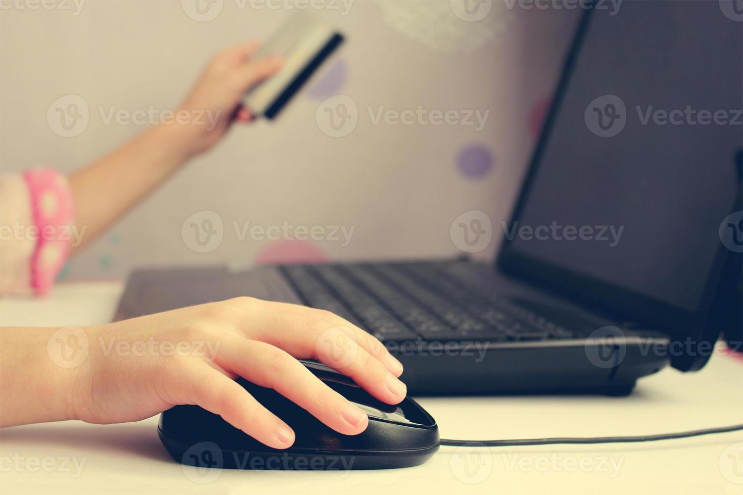 Close up of female hand on computer mouse and holding a credit card. The concept of online shopping. Toned image. photo