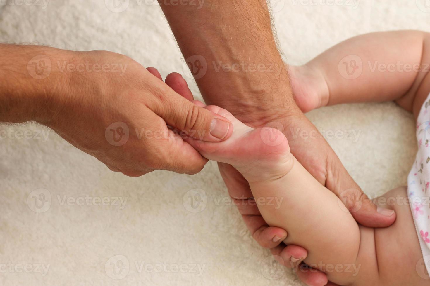 masajista haciendo masaje para pie pequeño bebé foto