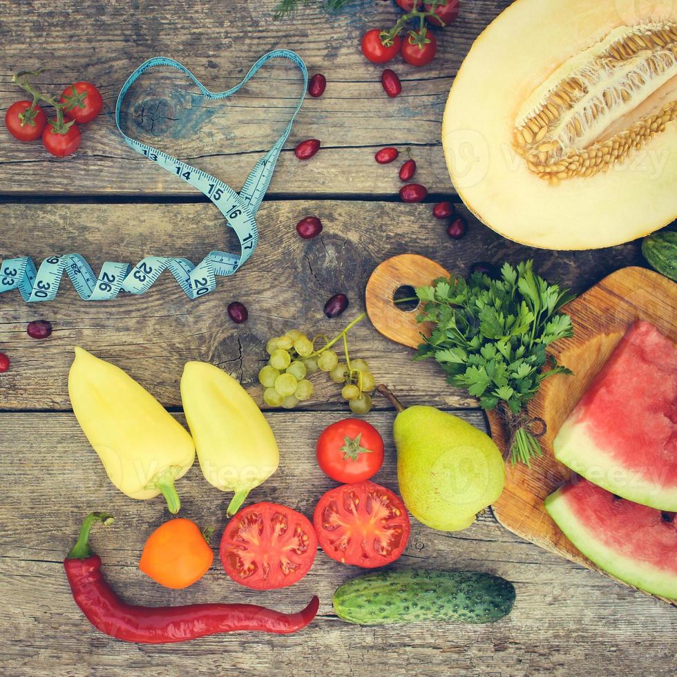 Fruits, vegetables and in measure tape in diet on wooden background. Toned image. photo