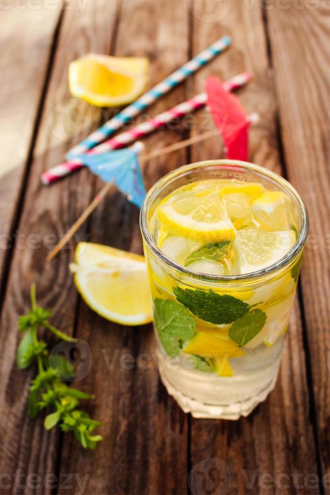 Drink with lemon, mint, ice, water on wooden background. Toned image photo