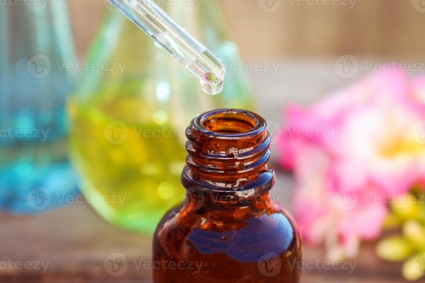 drop of oil dripping from pipette into bottles of essential oil photo