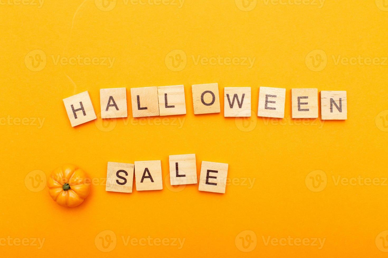 the inscription halloween sale with little pumpkin on orange background. photo