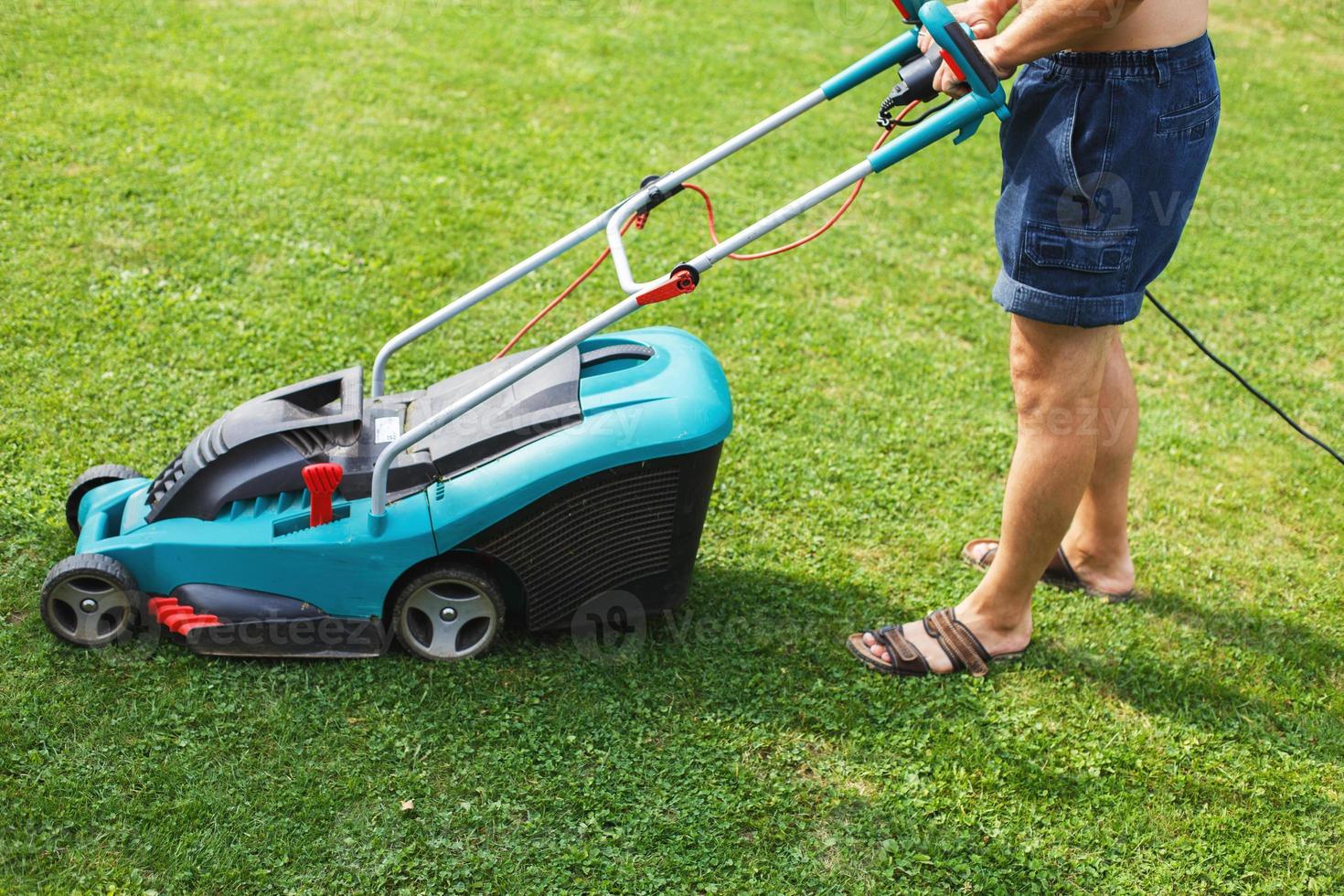 a man mows a lawn with a lawn mower photo