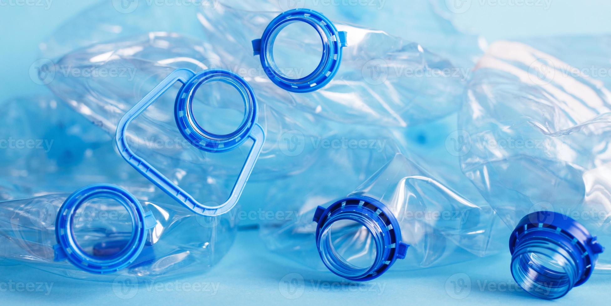 a lot of plastic empty rumpled used bottles on a blue background. waste and pollution concept photo