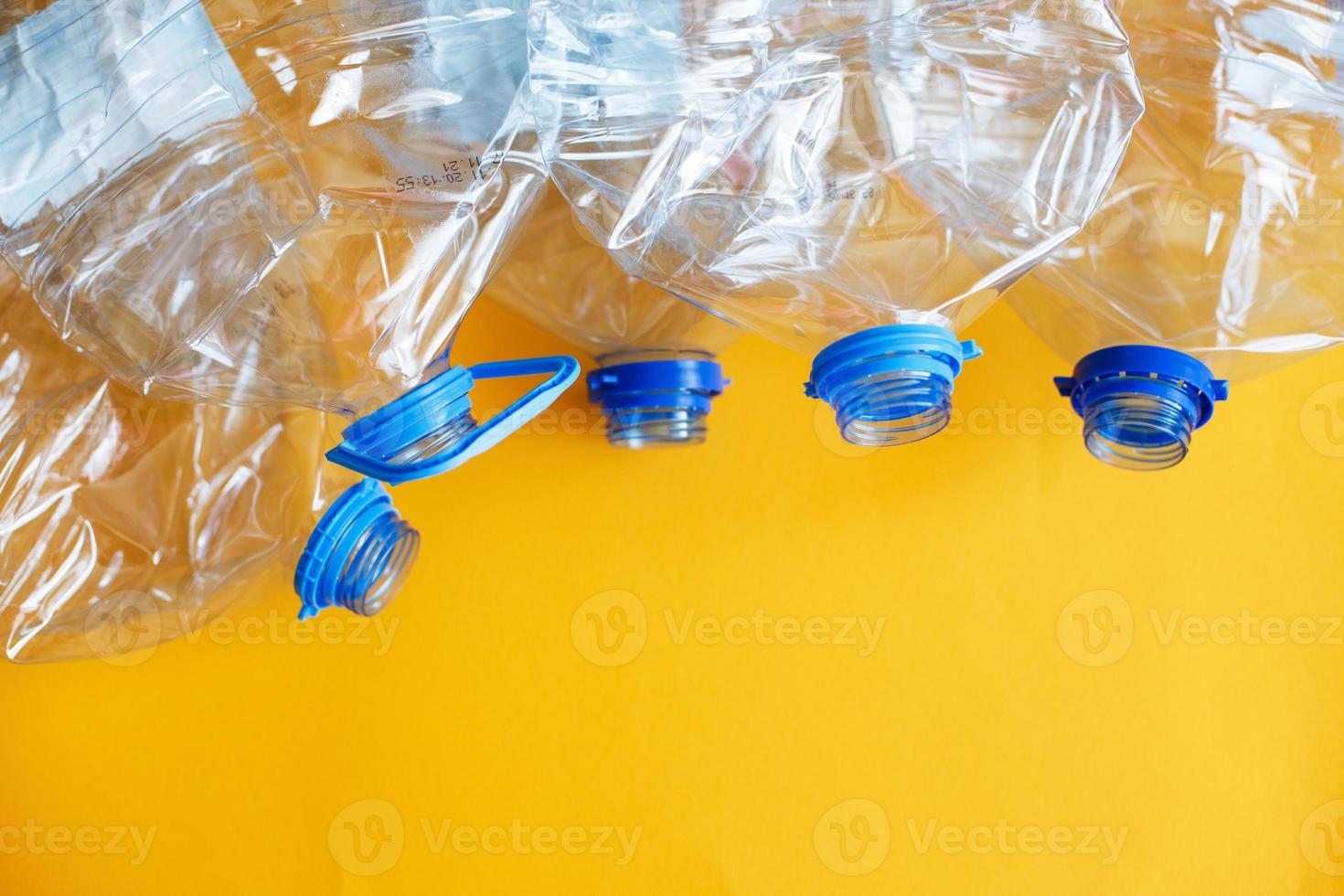 a lot of plastic empty rumpled used bottles on a yellow background. waste and pollution concept photo