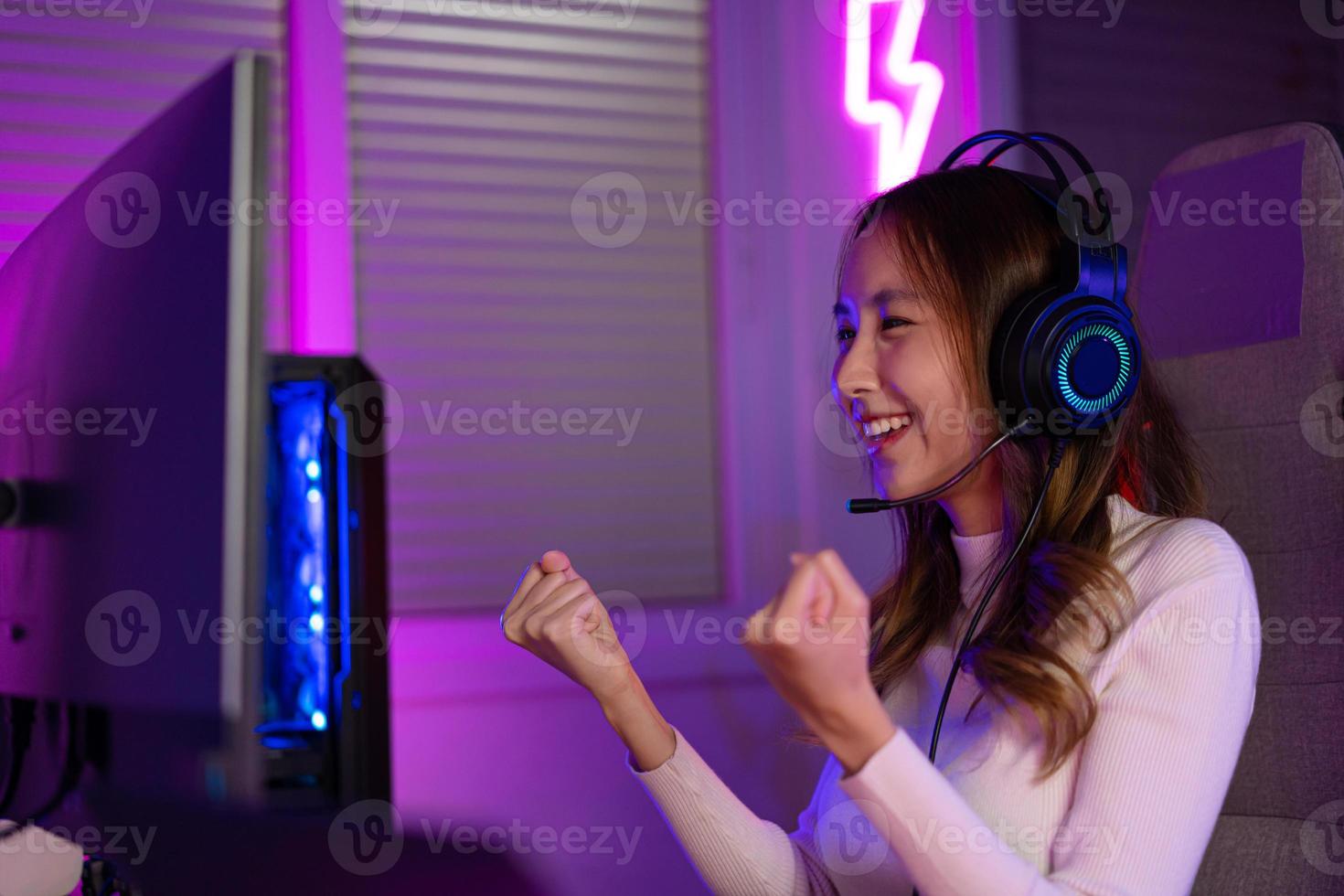 Asian gamer playing online video game winning excited on PC with lighting effect, broadcast streaming live at home. Gamer and E-Sport online gaming technology Championship tournament gamer concept. photo