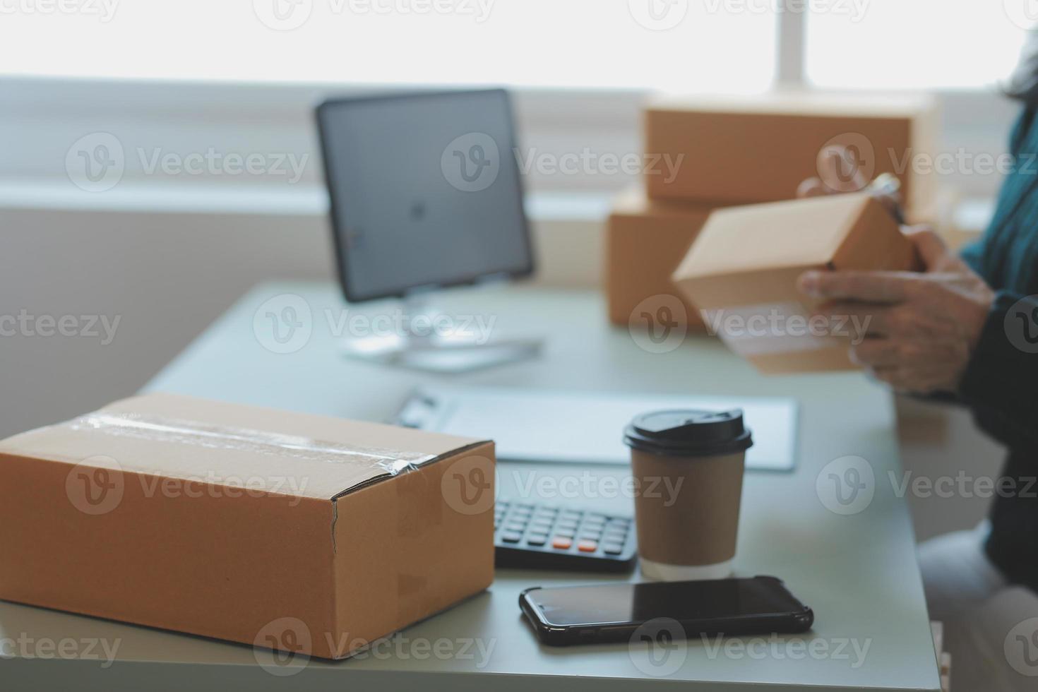 Startup SME small business entrepreneur of freelance Asian woman wearing apron using laptop and box to receive and review orders online to prepare to pack sell to customers, online sme business ideas. photo