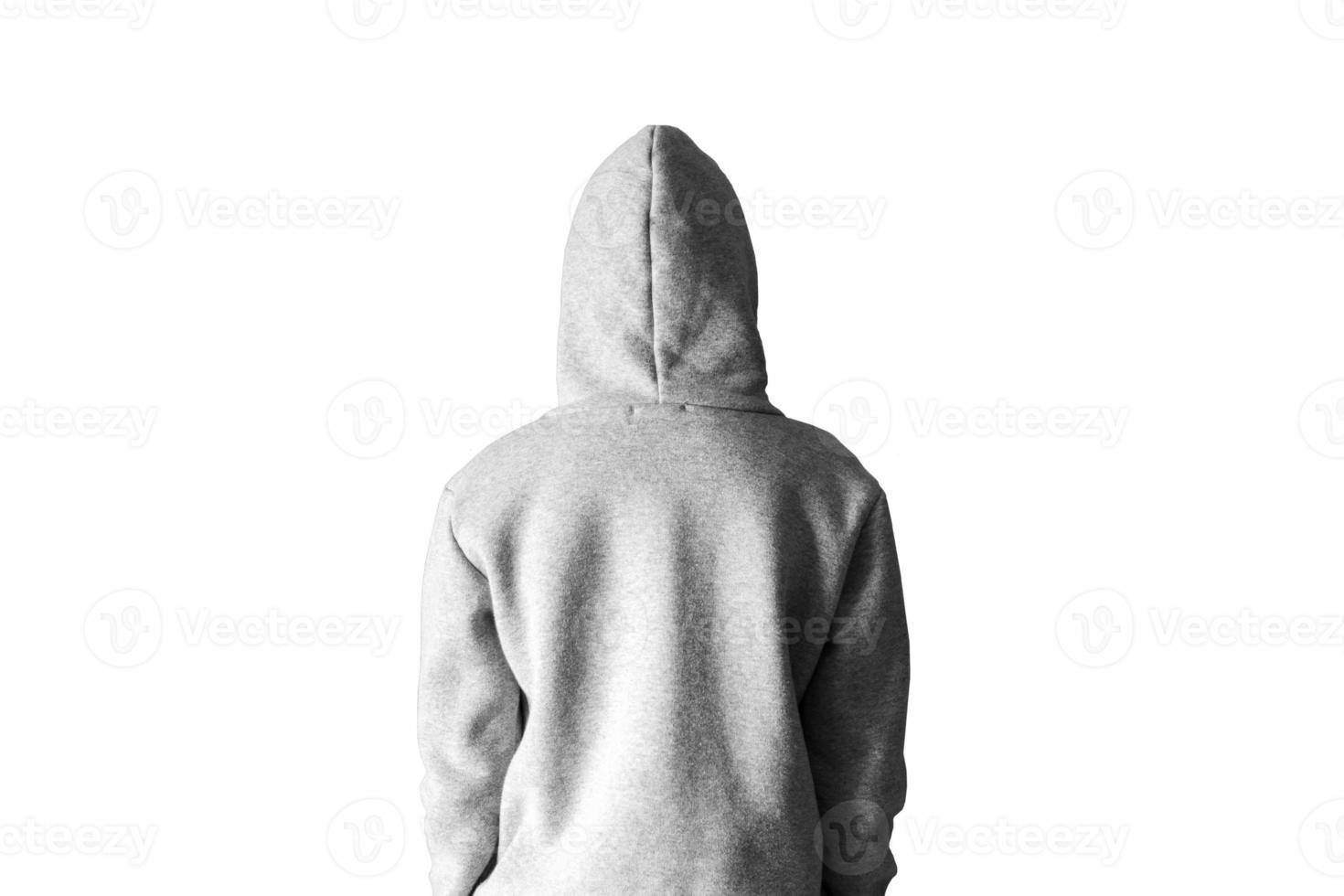 A man in a gray hoodie in a hood on a white background stands with his back. photo