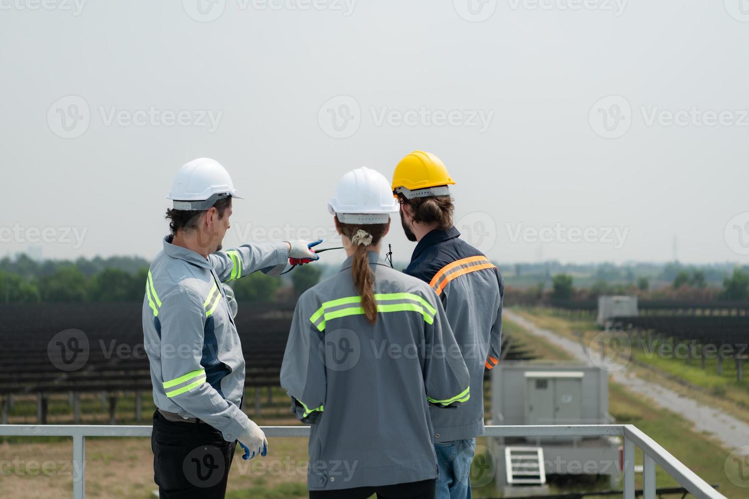 On the rooftop of a large solar energy storage station building A team of electric power engineers inspecting solar panels that have been installed on hundreds of acres of fields. photo