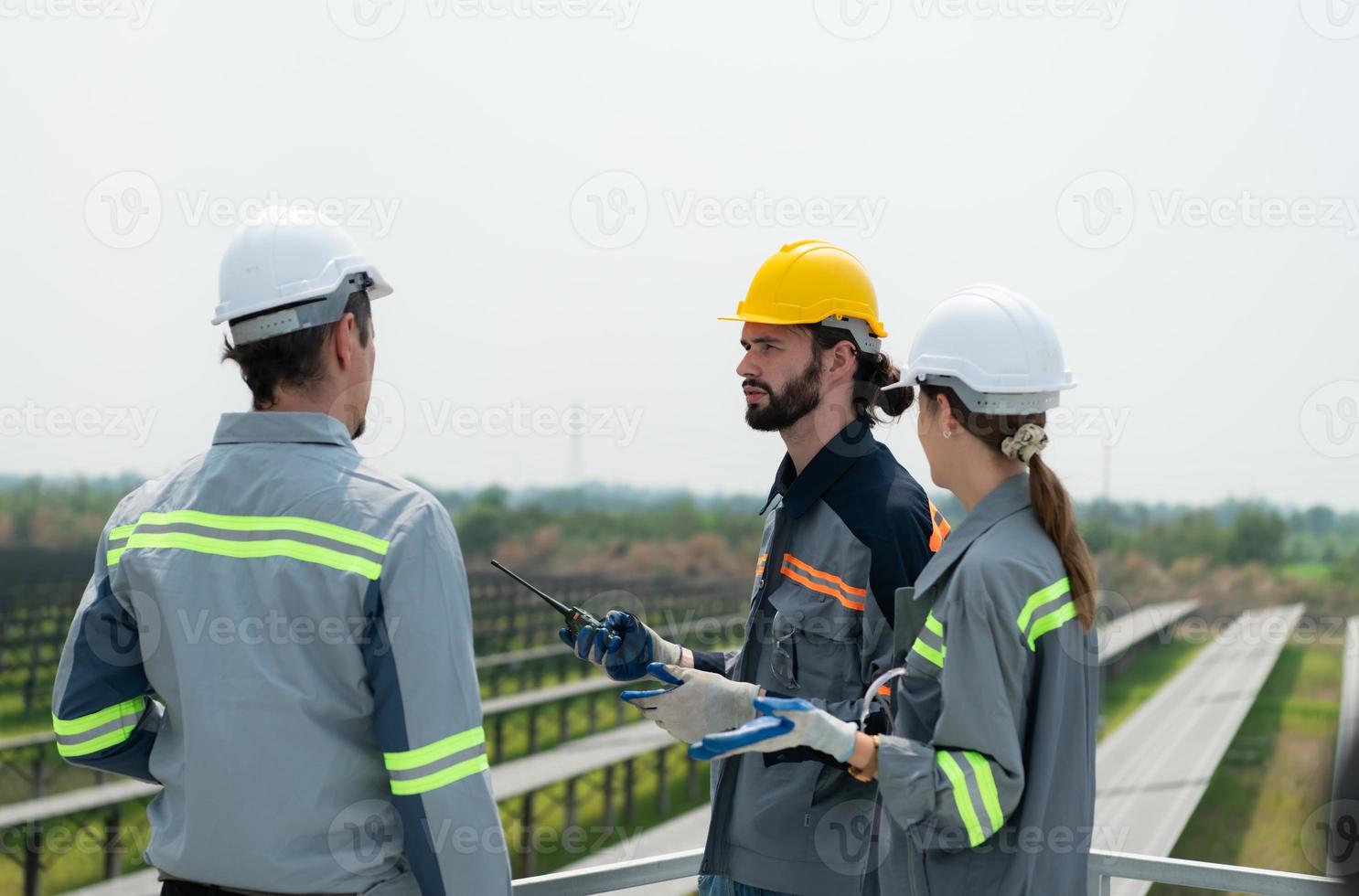 On the rooftop of a large solar energy storage station building A team of electric power engineers inspecting solar panels that have been installed on hundreds of acres of fields. photo