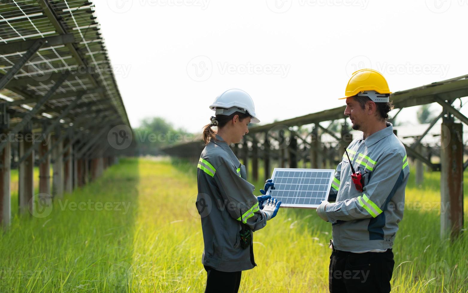 At hundreds of acres of grass with solar panels A team of electric power engineers is testing a prototype of a small solar panel installed on this field. photo