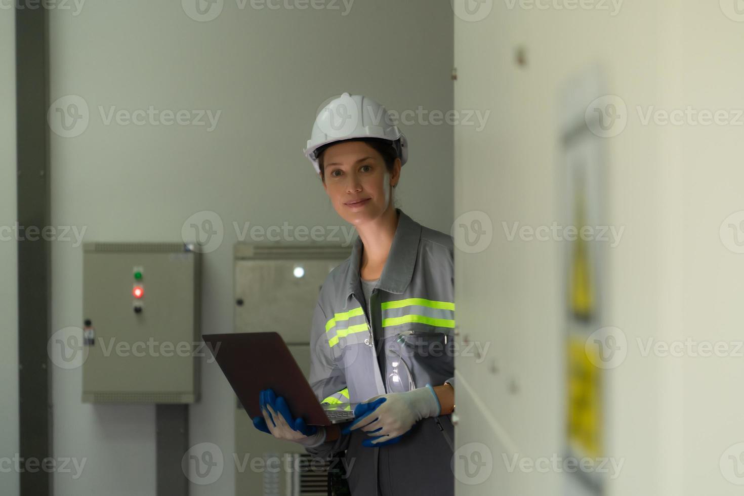 Young female engineer inspecting system of a large solar energy storage station in the middle of the field of solar cells on an area of hundreds of acres photo