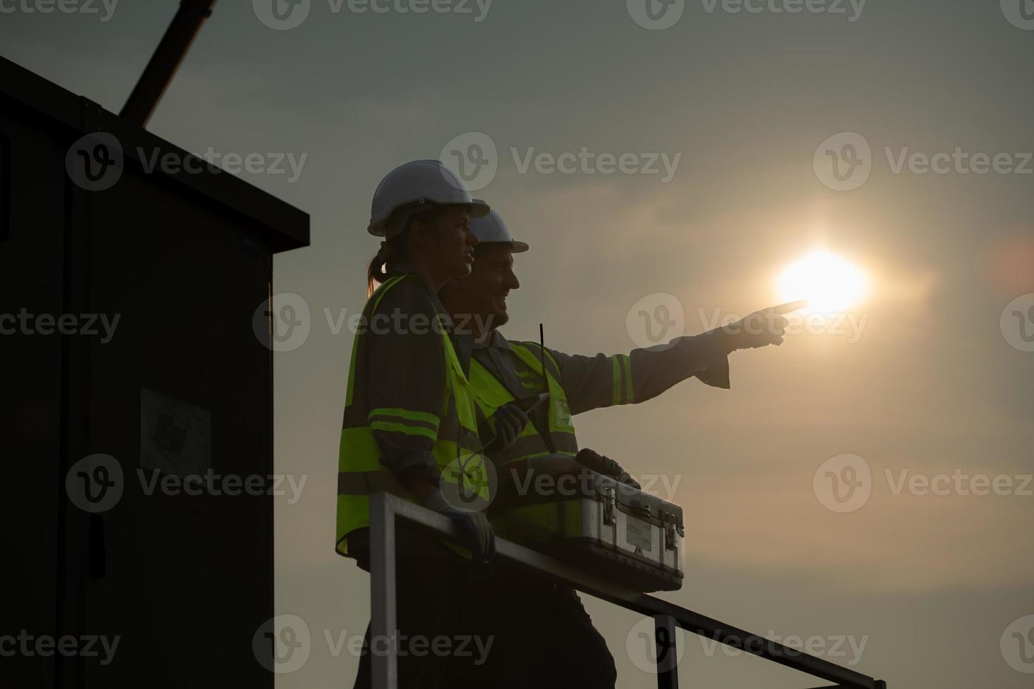 A team of electrical engineers inspecting solar panels in a hundred acre field, in the evening after completing the daily work tasks with the setting sun. photo