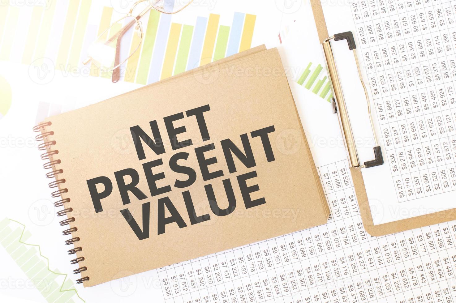 Business up graph on a sheet of craft colour Notepad with net present value sign. Notepad on desk with financial documentation photo