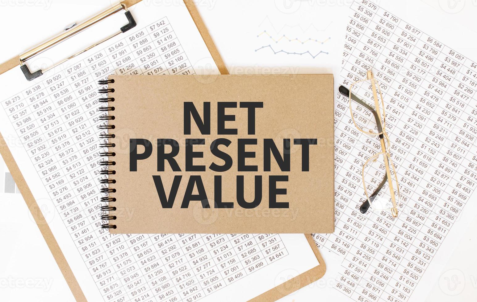 Craft colour notepad with text net present value. Notepad with eyeglasses and text documents. Business concept photo