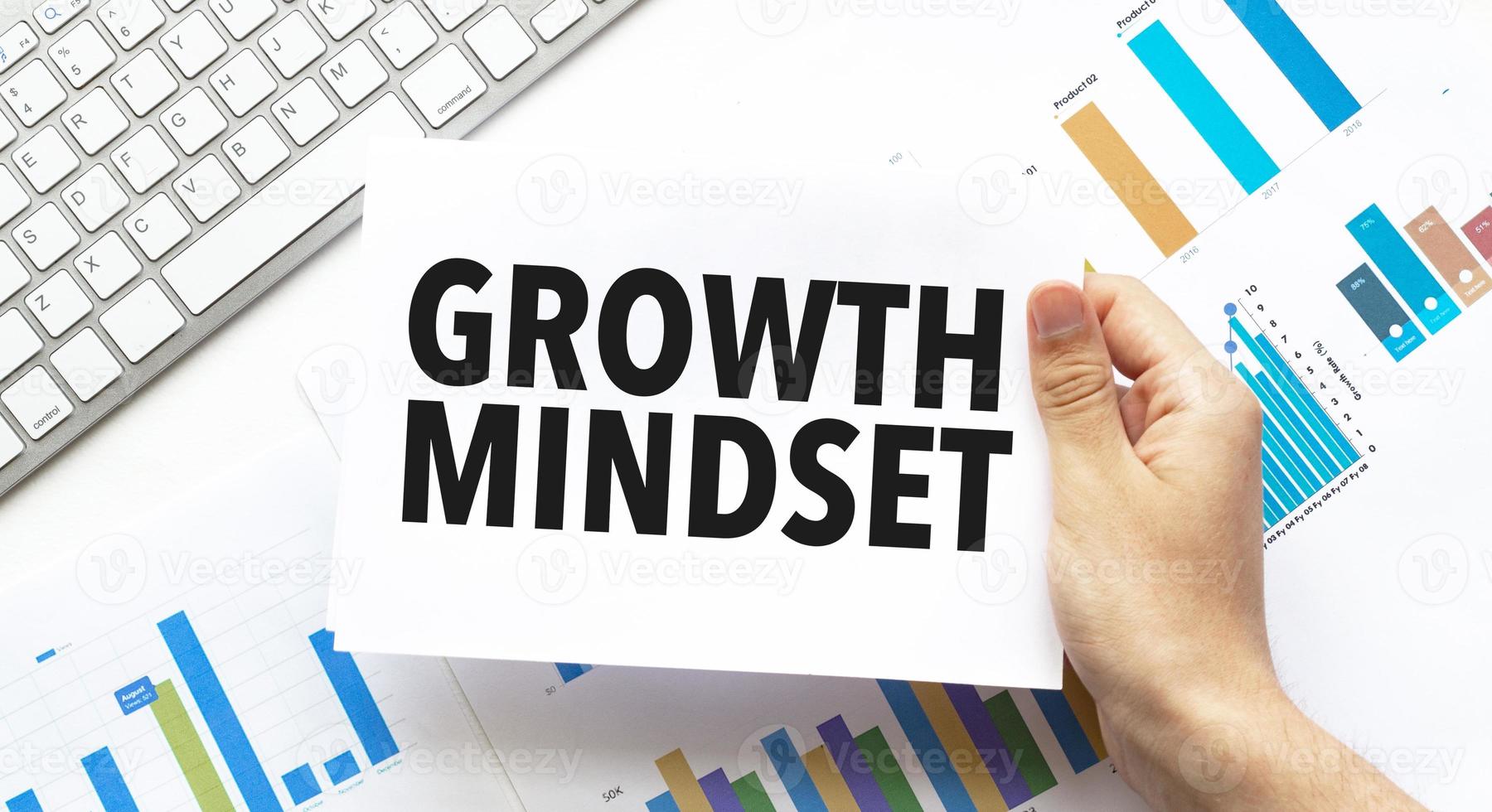 Businessman holding a card with text growth mindset .Keyboard, diagram and white background photo
