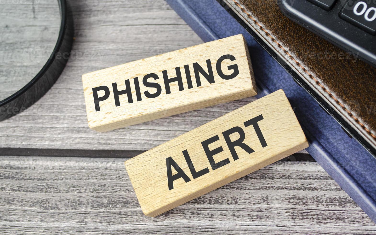 phishing alert . text on wooden blocks on wooden background with office supplies photo