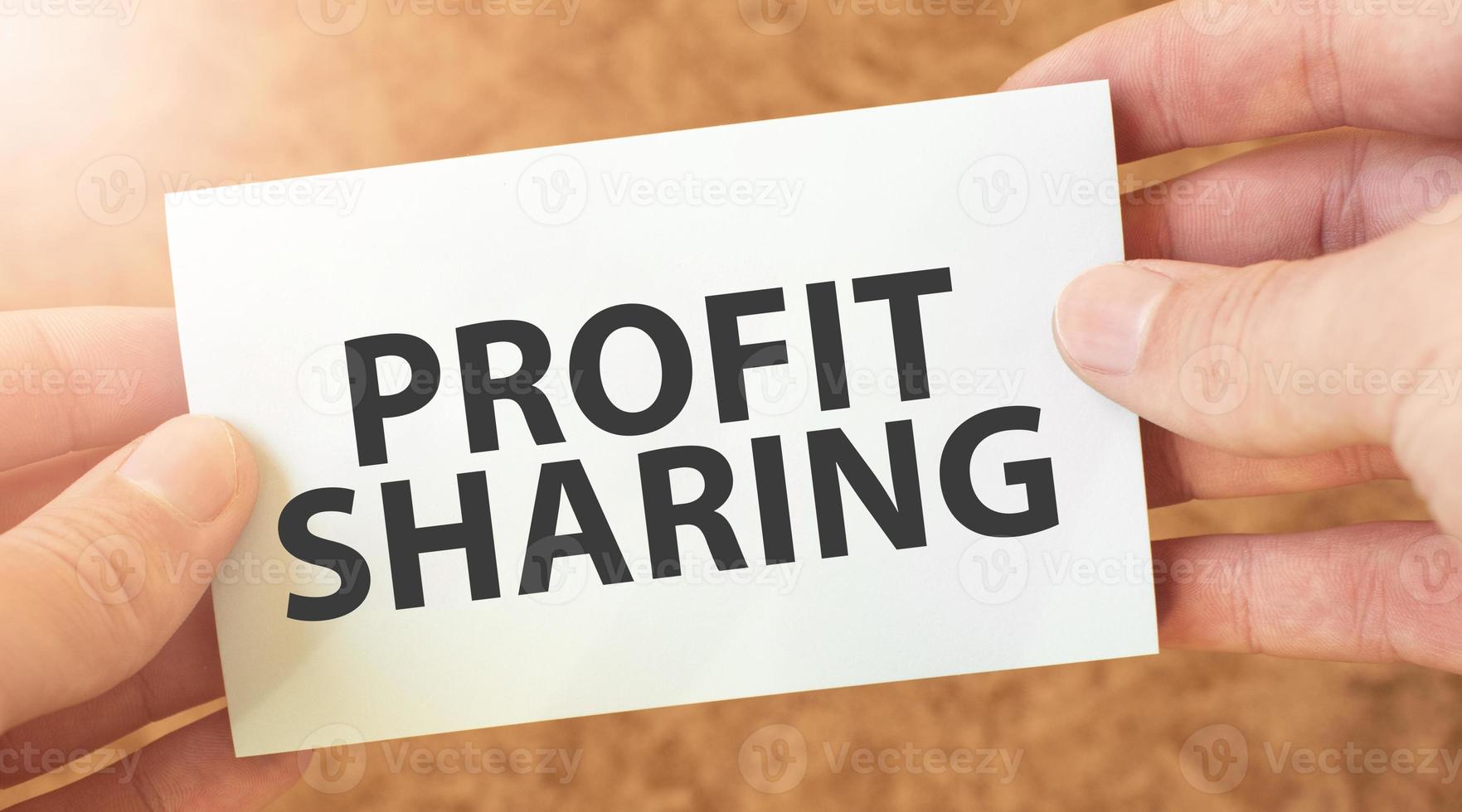 profit sharing word inscription on white card paper sheet in hands of a businessman. recap concept. red and white paper photo