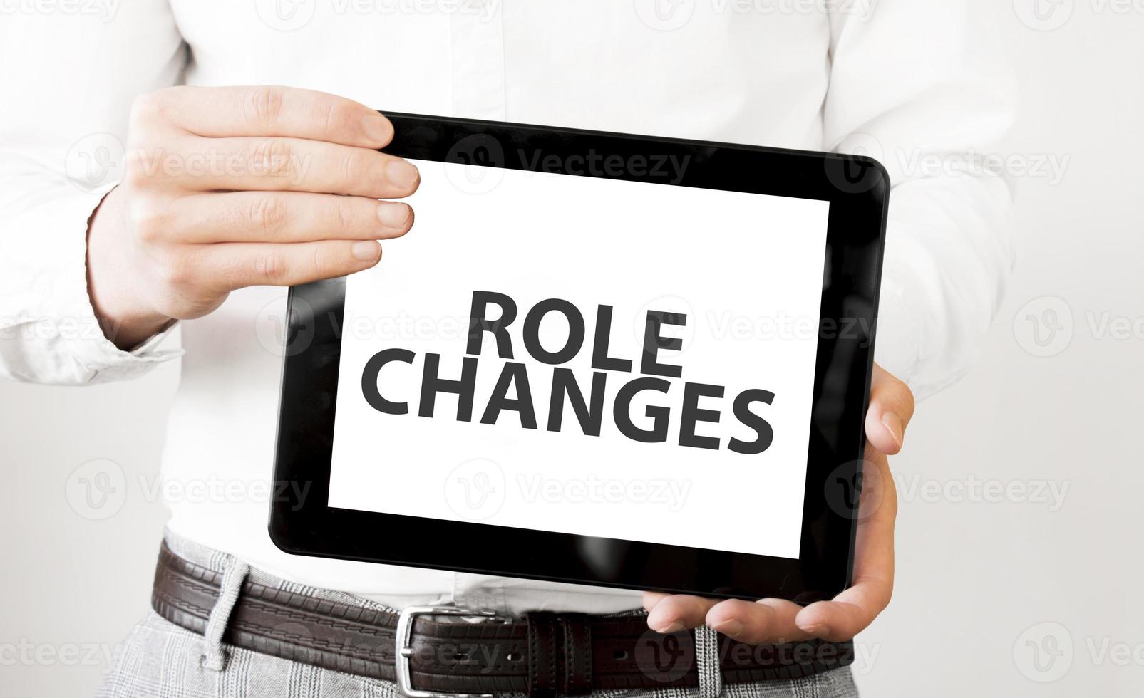Text Role changes on tablet display in businessman hands on the white background. Business concept photo