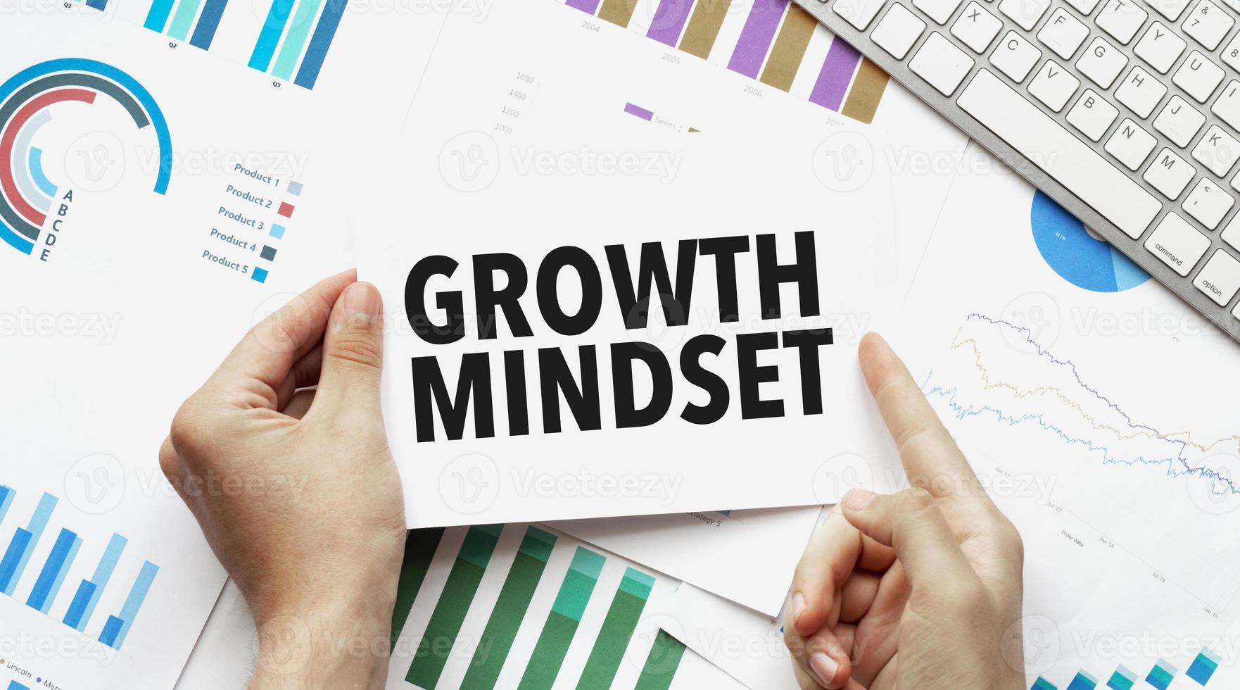 Businessman holding a card with text growth mindset .Keyboard, diagram and white background photo