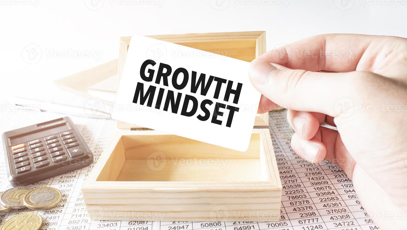 Businessman hold white card with text growth mindset Calculator, wood box, money and financial documents photo
