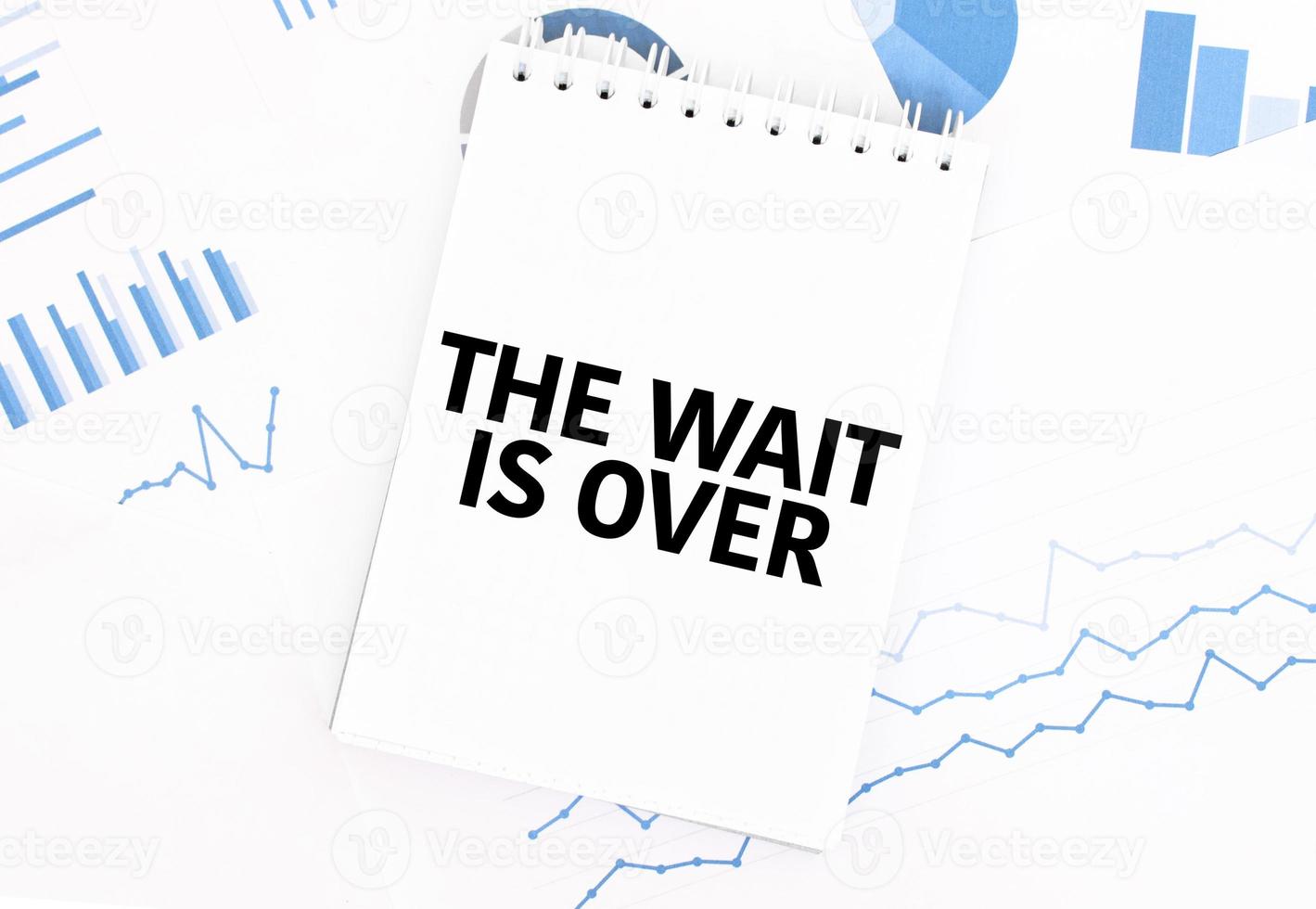 White notepad with text the wait is over on the financial documentation. Finance and business concept photo