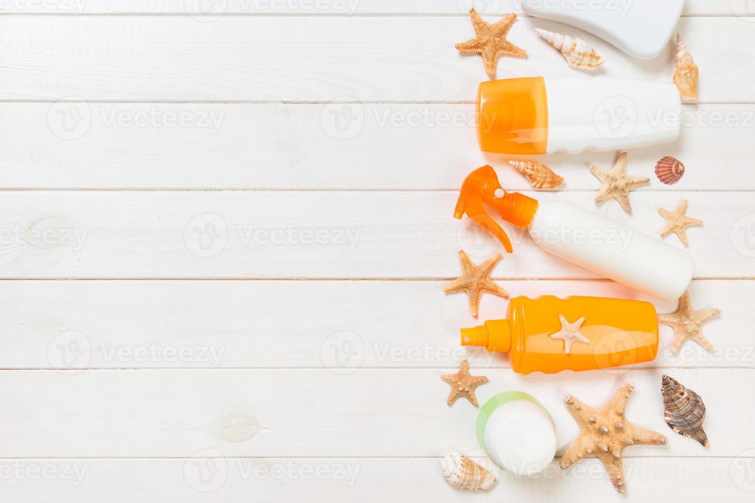 flat lay concept summer travel vacation. Sunscreen bottles with starfish on white wooden table with copy space photo