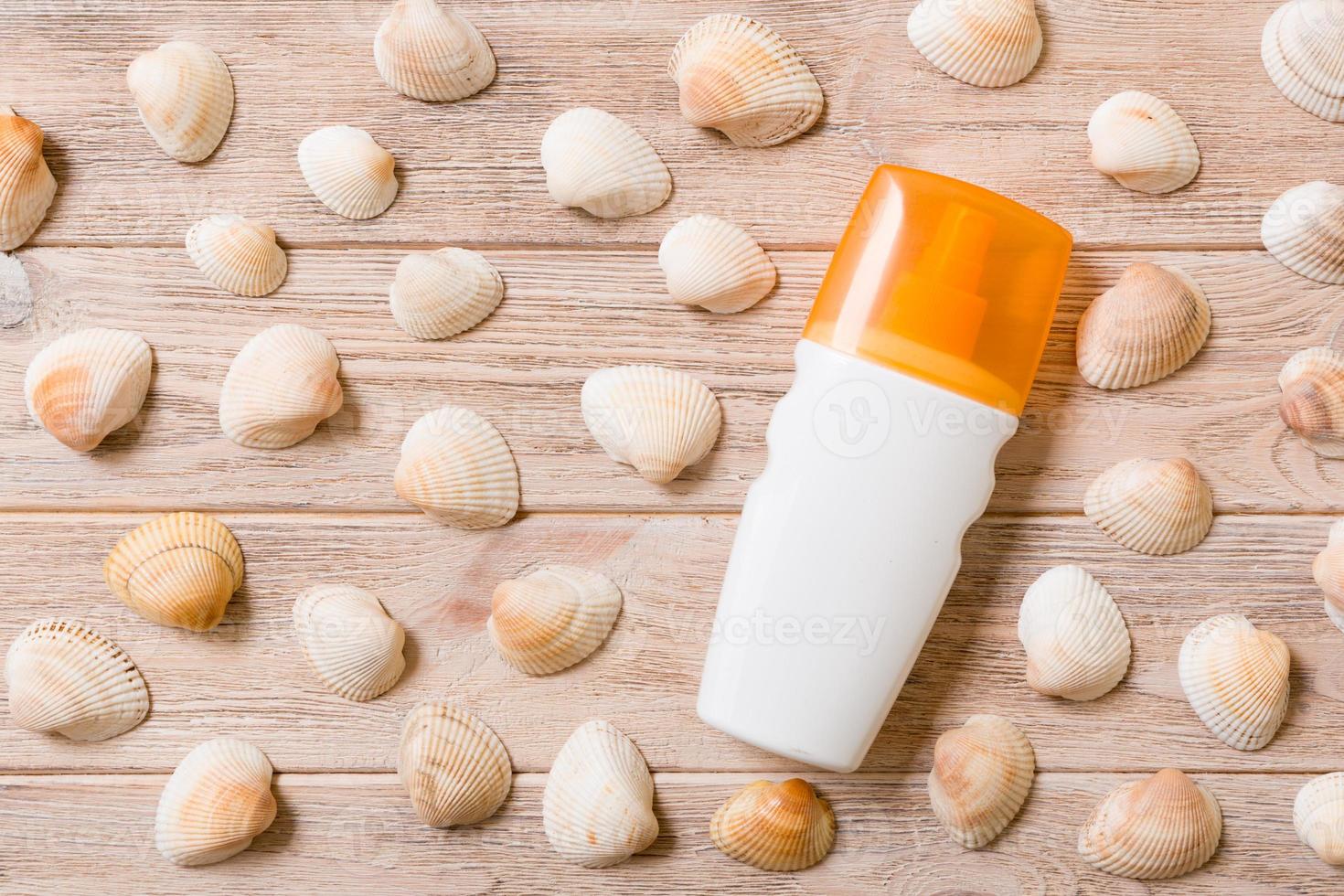 Top view of sunscreen bottle with seashells on wooden board background with copy space. flat lay concept of summer travel vacation photo