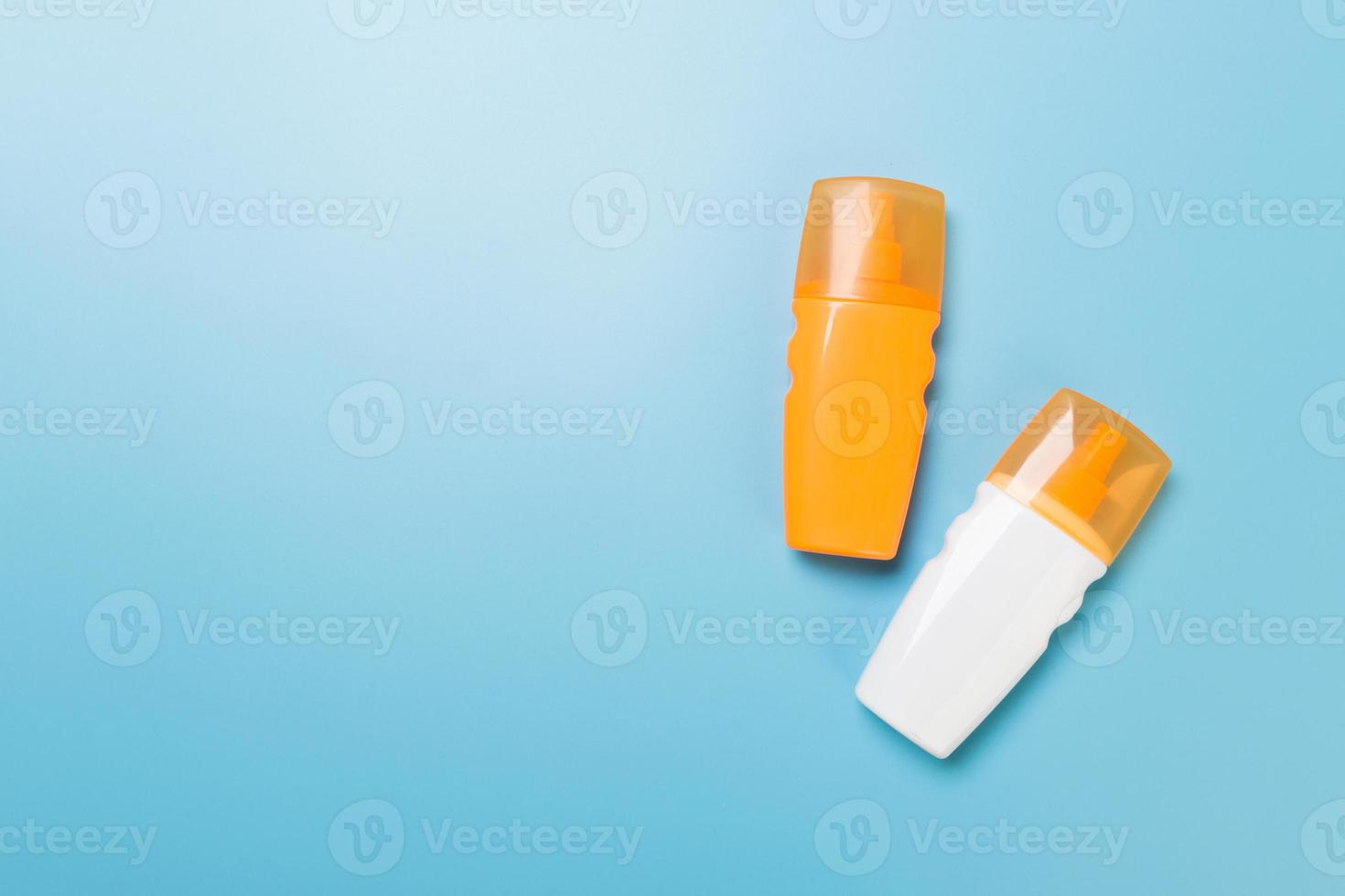 flat lay concept of summer travel vacation. Sunscreen bottle mock up on blue background top view with copy space photo