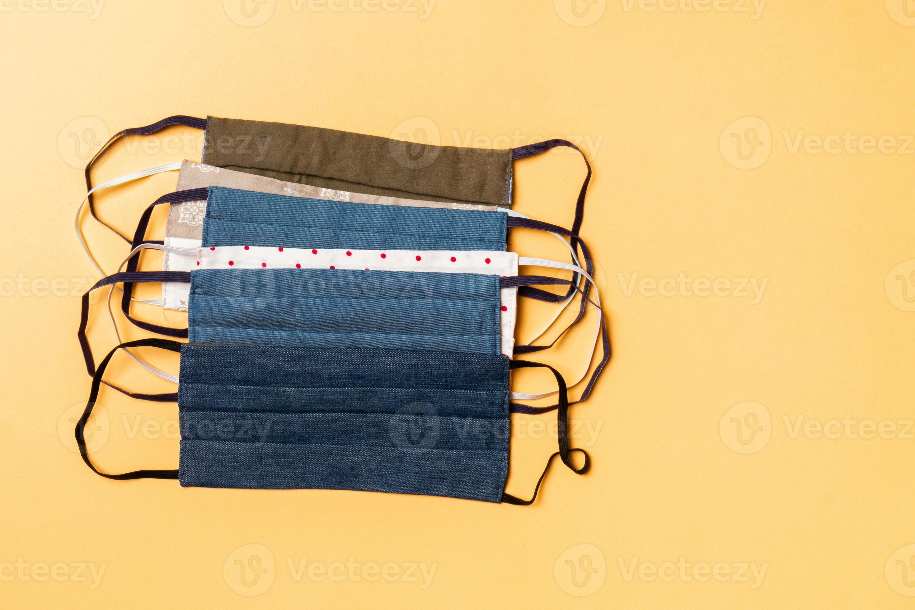Top view of a heap of homemade cotton reusable masks on orange