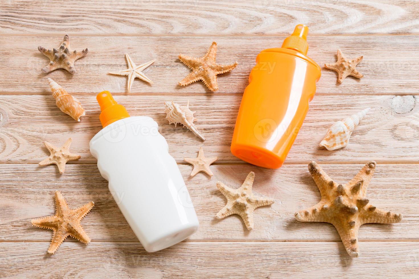 Top view of sunscreen bottle with seashells and starfish on wooden board background with copy space. flat lay concept of summer travel vacation photo