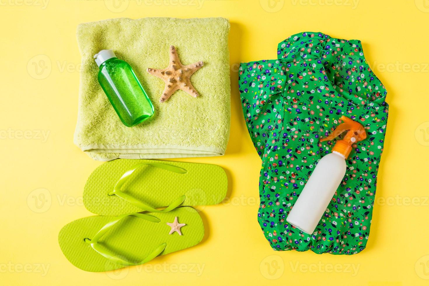 Flat lay composition with green Beach accessories on yellow color background. Summer holiday background. Vacation and travel items top view photo