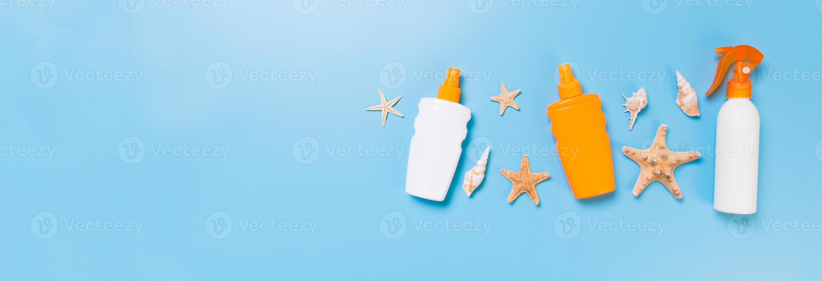 Sunscreen bottles with seashells on blue table top view photo