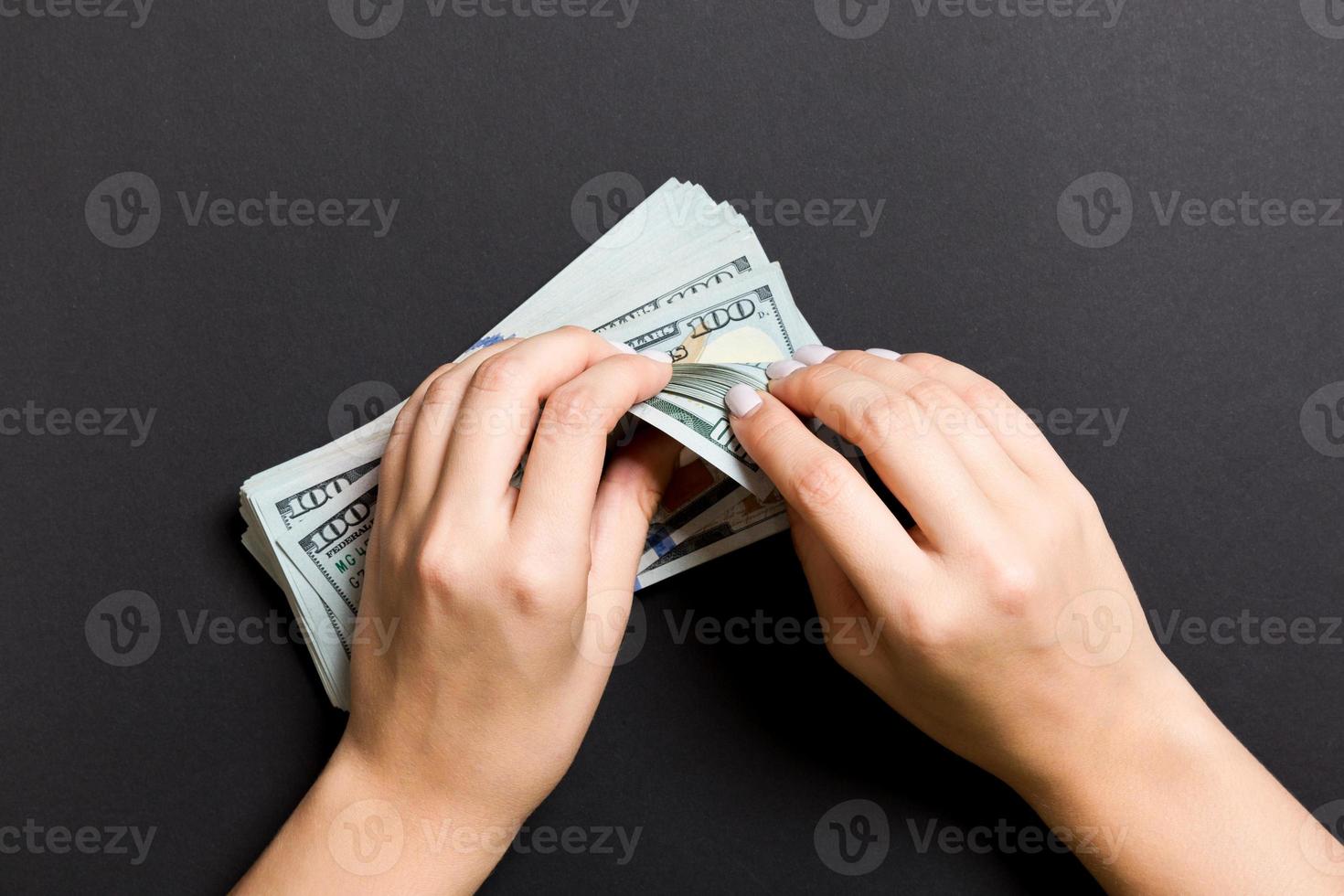 Top view of a businesswoman's hands counting one hundred dollar banknotes on colorful background. Success and wealth concept photo