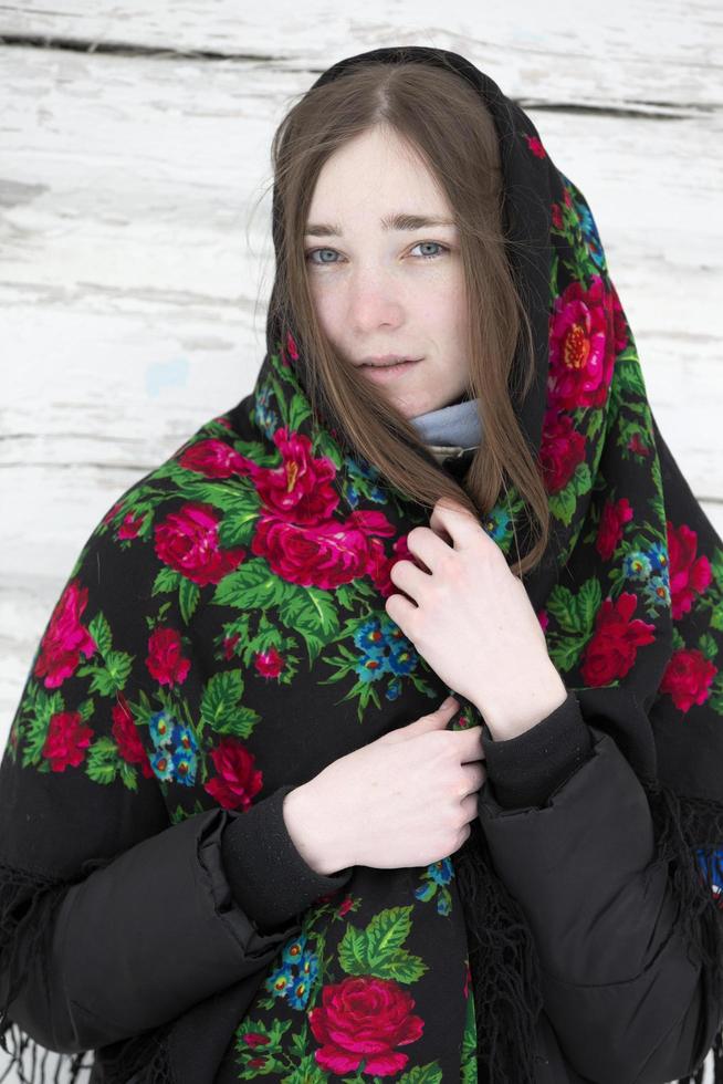 March 13, 2021. Belarus, Nadezhda village, Maslyanitsa holiday.Portrait of a beautiful girl in a Russian headscarf. Young woman . Russian village in winter. photo