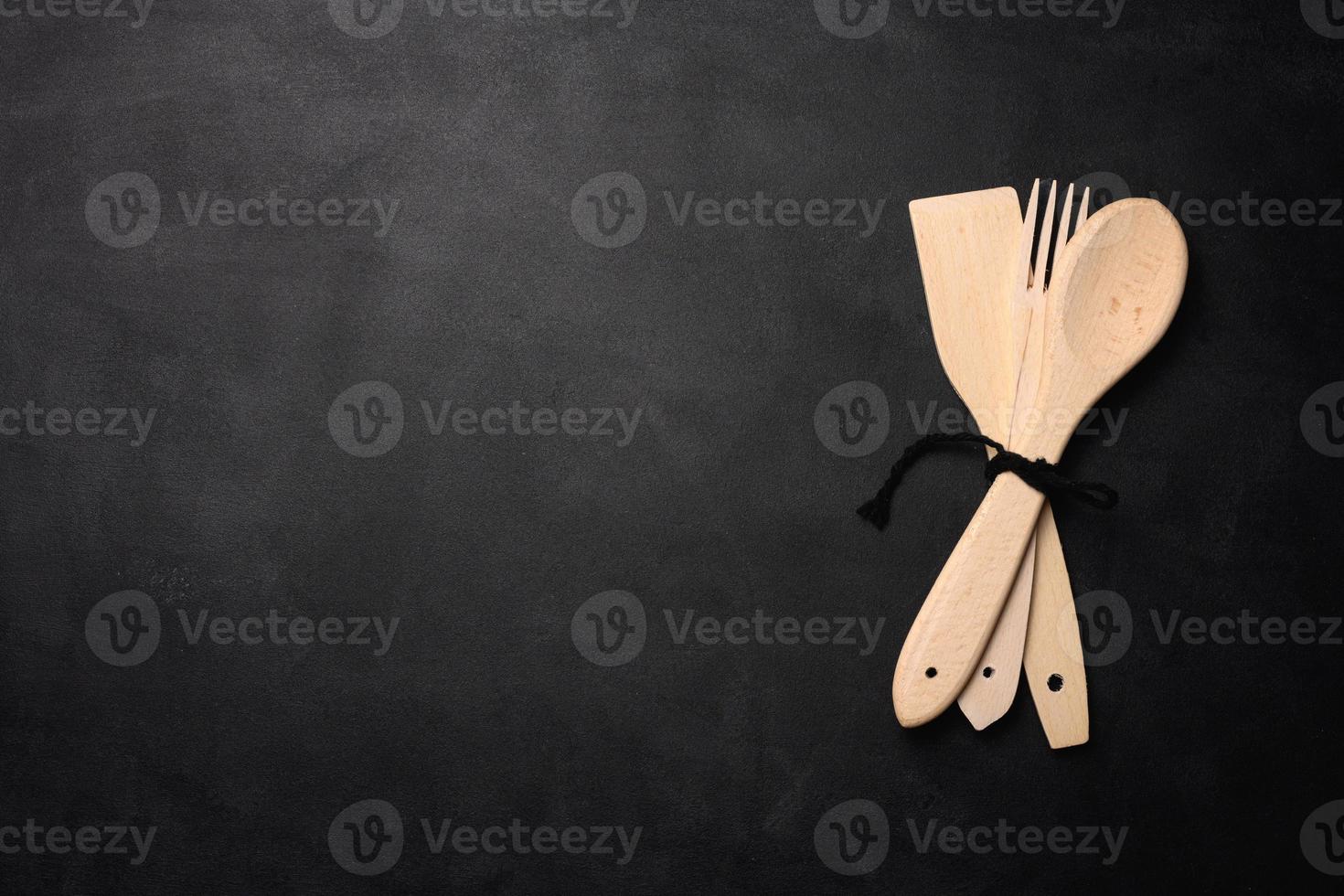 Fork and empty wooden spoon on a a black background, top view. photo